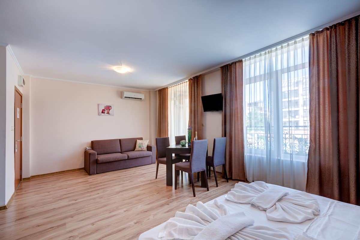 Ein Hotelzimmer mit einem Bett, einer Couch, einem Esstisch mit Stühlen und einem Fernseher an der Wand.