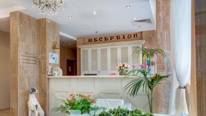 A reception area with a marble reception desk, a dog statue, and a potted plant. - Apart-hotel Dawn Park (Sunny Beach)
