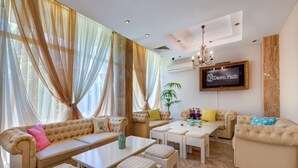 A spacious living area with a sofa set, a coffee table, and a TV mounted on the wall. - Apart-hotel Dawn Park (Sunny Beach)