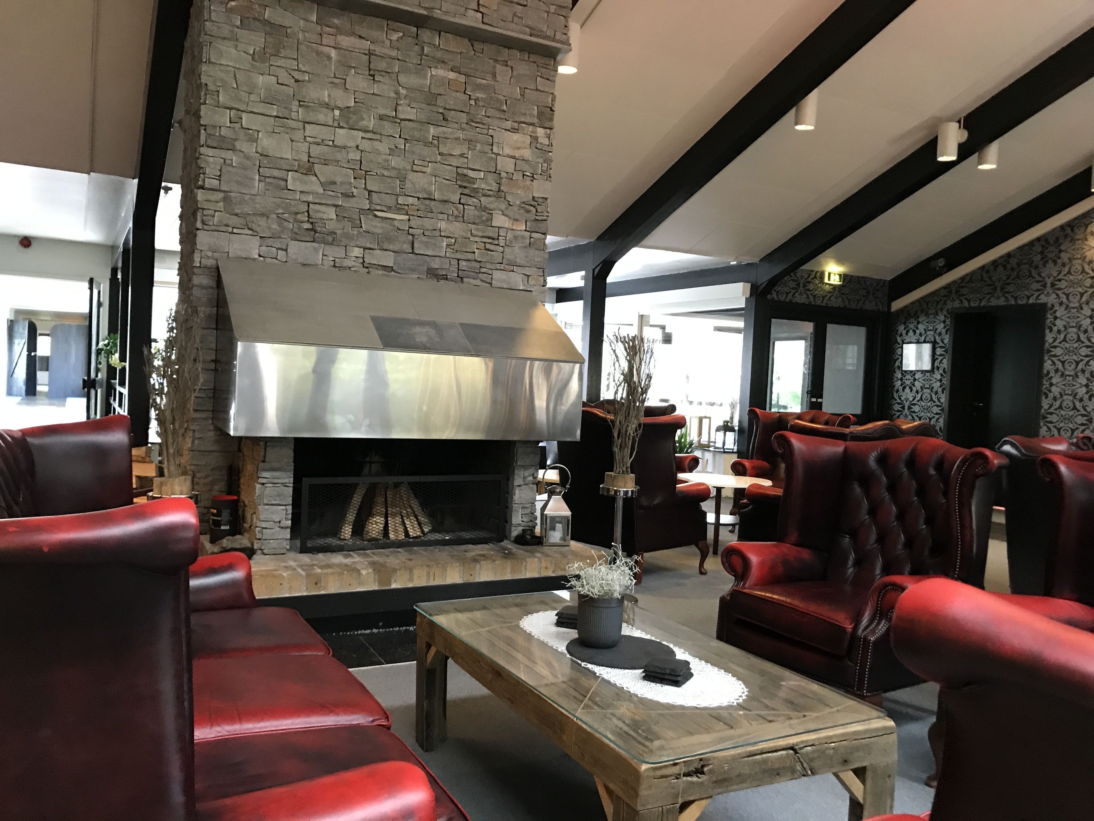 A modern lounge area with leather sofas, a wooden coffee table, and a stone fireplace.