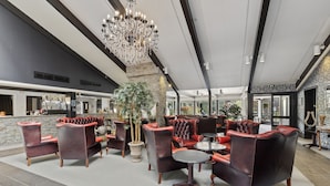 A spacious lobby with leather armchairs, a chandelier, and a stone fireplace.