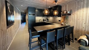 A modern kitchen with a central island, black cabinetry, and pendant lighting.
