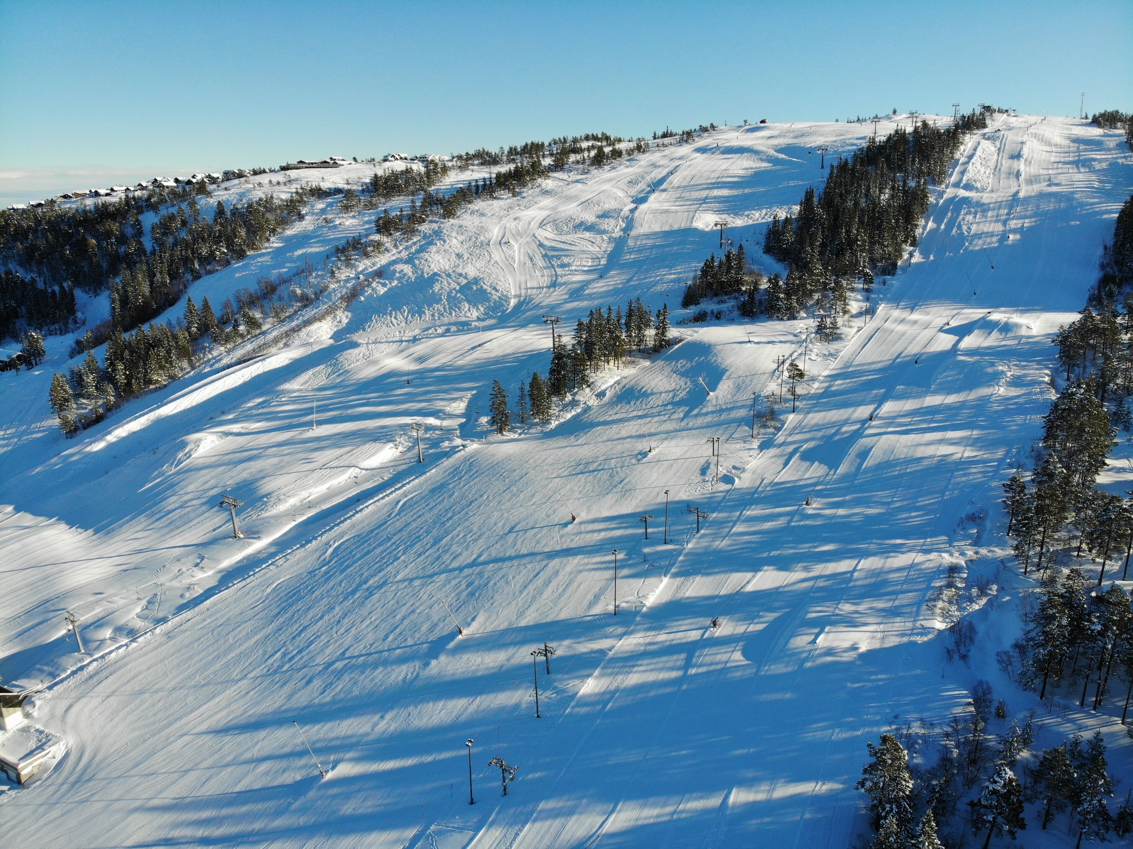 A snow-covered ski slope with ski lifts and trees.