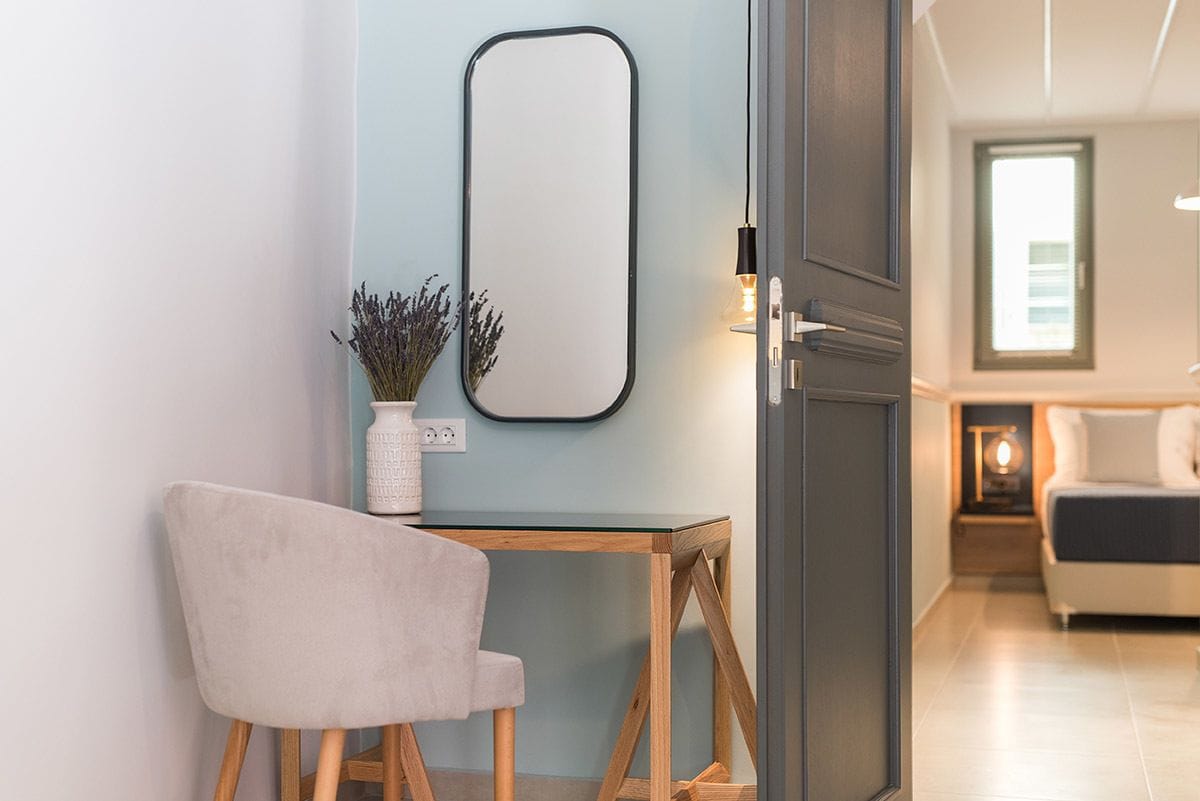 A modern room with a wooden table, a chair, a mirror, and a door leading to another room.
