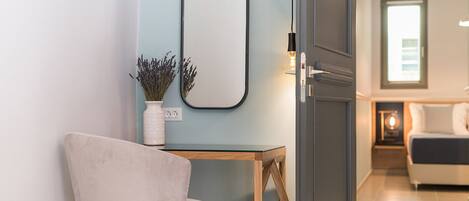 A modern room with a wooden table, a chair, a mirror, and a door leading to another room.