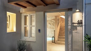 Una entrada moderna con una escalera de piedra, una planta en maceta y una cerradura digital.