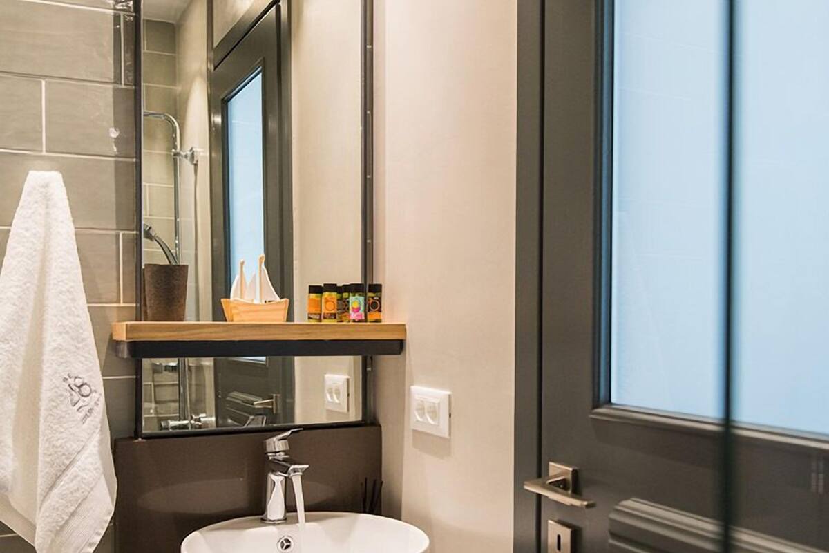 Un baño moderno con un espejo grande, un lavamanos blanco y una toalla colgada en la pared.