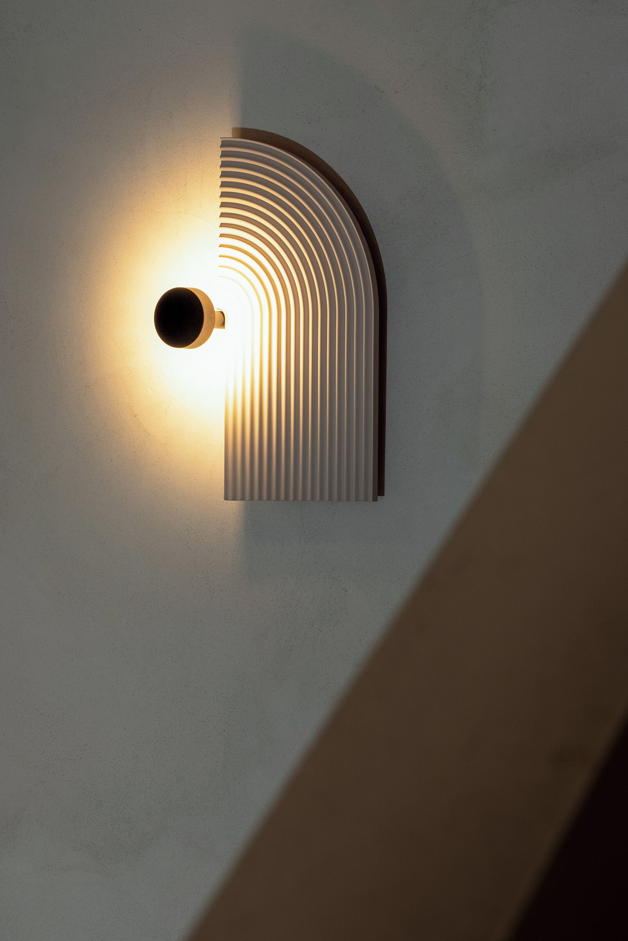A wall-mounted light fixture with a curved design and a circular element.