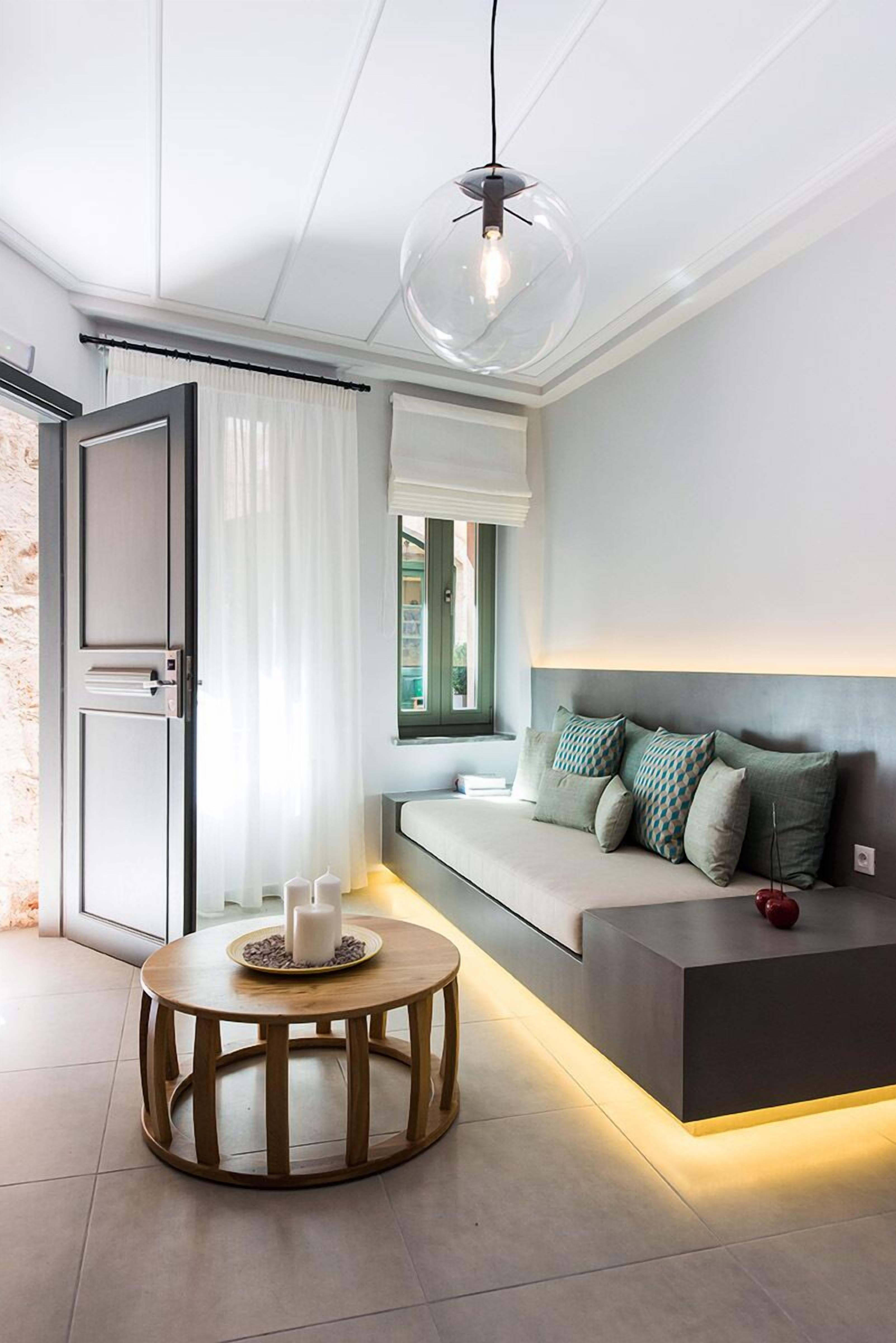 A modern living room with a sofa, round wooden coffee table, and a pendant light.