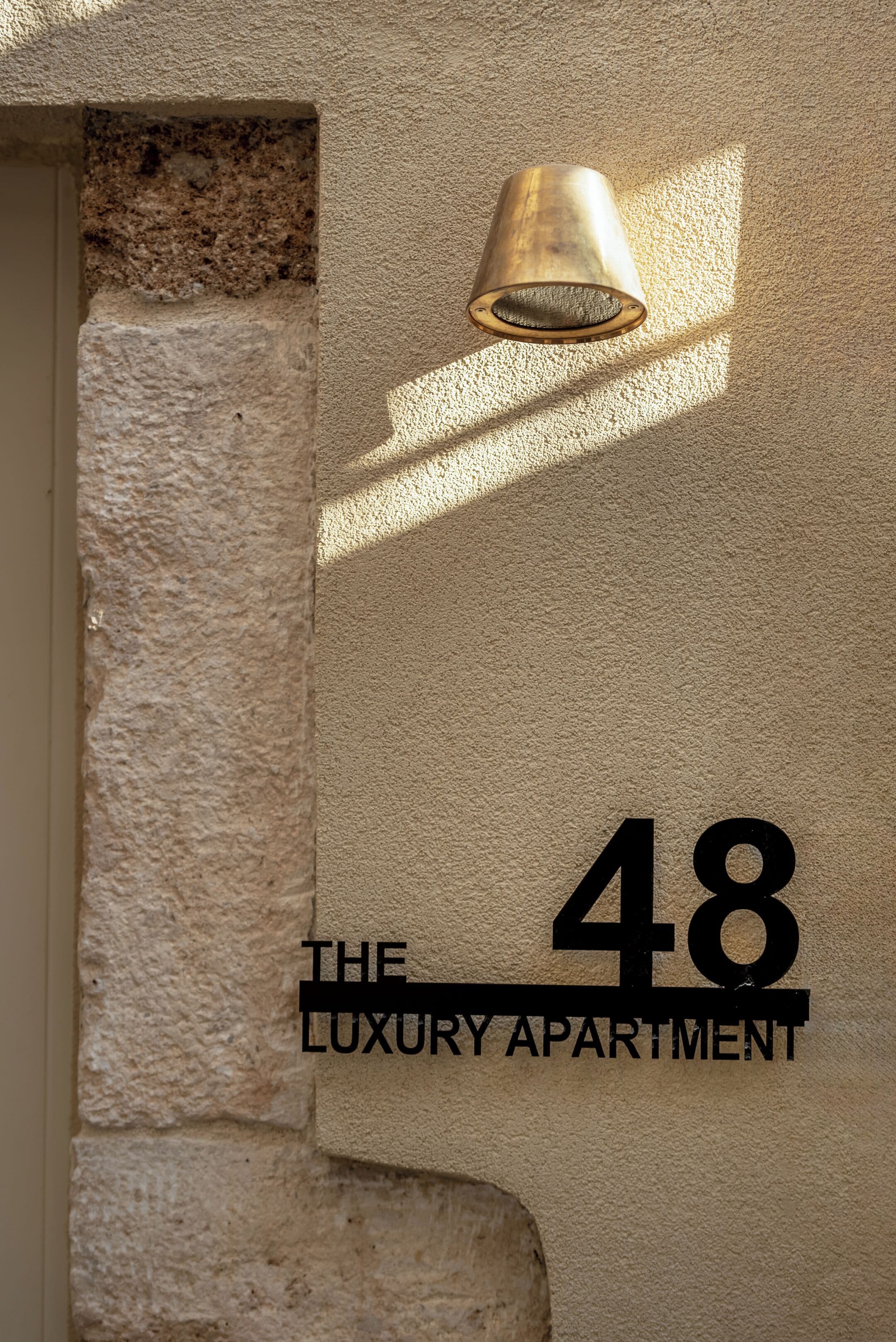 Een gestructureerde muur met het cijfer '48' en de tekst 'THE LUXURY APARTMENT', wat een luxe wooneenheid aanduidt.