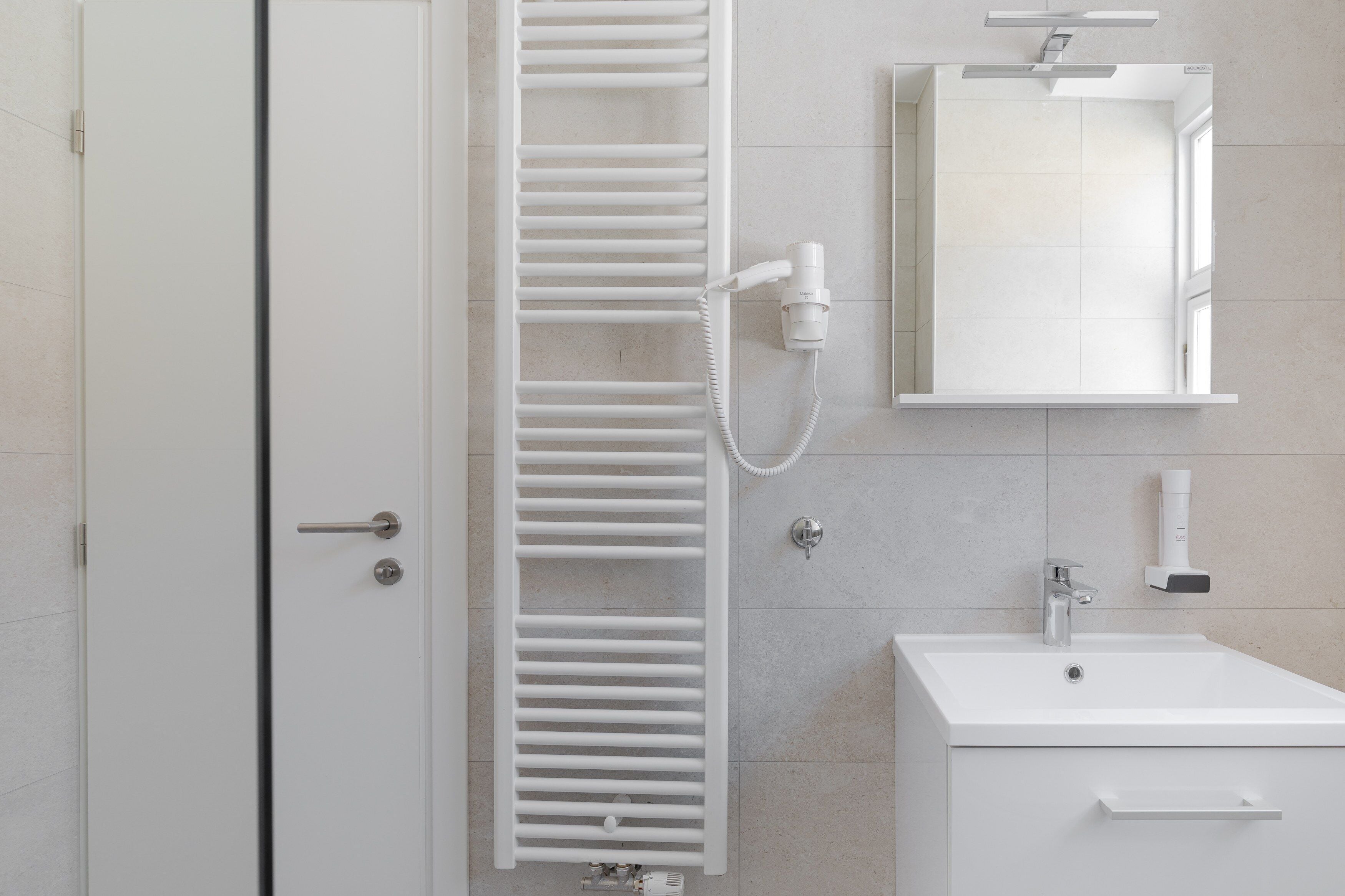 A bathroom with a white shower, a sink, and a mirror.