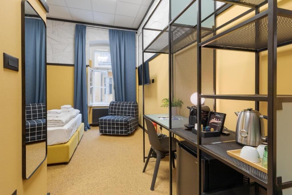 A compact hotel room with a bed, a sofa, a desk with a computer, and a TV.