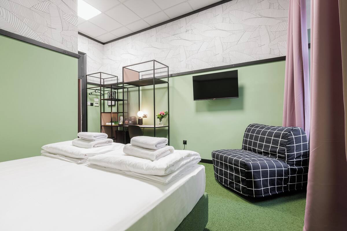 Ein Hotelzimmer mit einem Bett, einer Sitzecke, einem Fernseher und einem grünen Teppich.