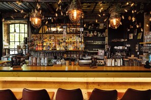 A bar with a wooden counter, multiple bottles, glasses, and a variety of bar tools. - Stay Swanky (Zagreb)