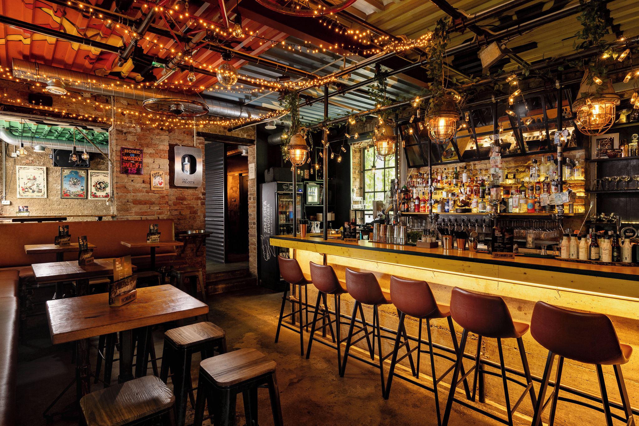 Eine Bar mit Holzhockern, einer Theke und verschiedenen Flaschen und Gläsern.