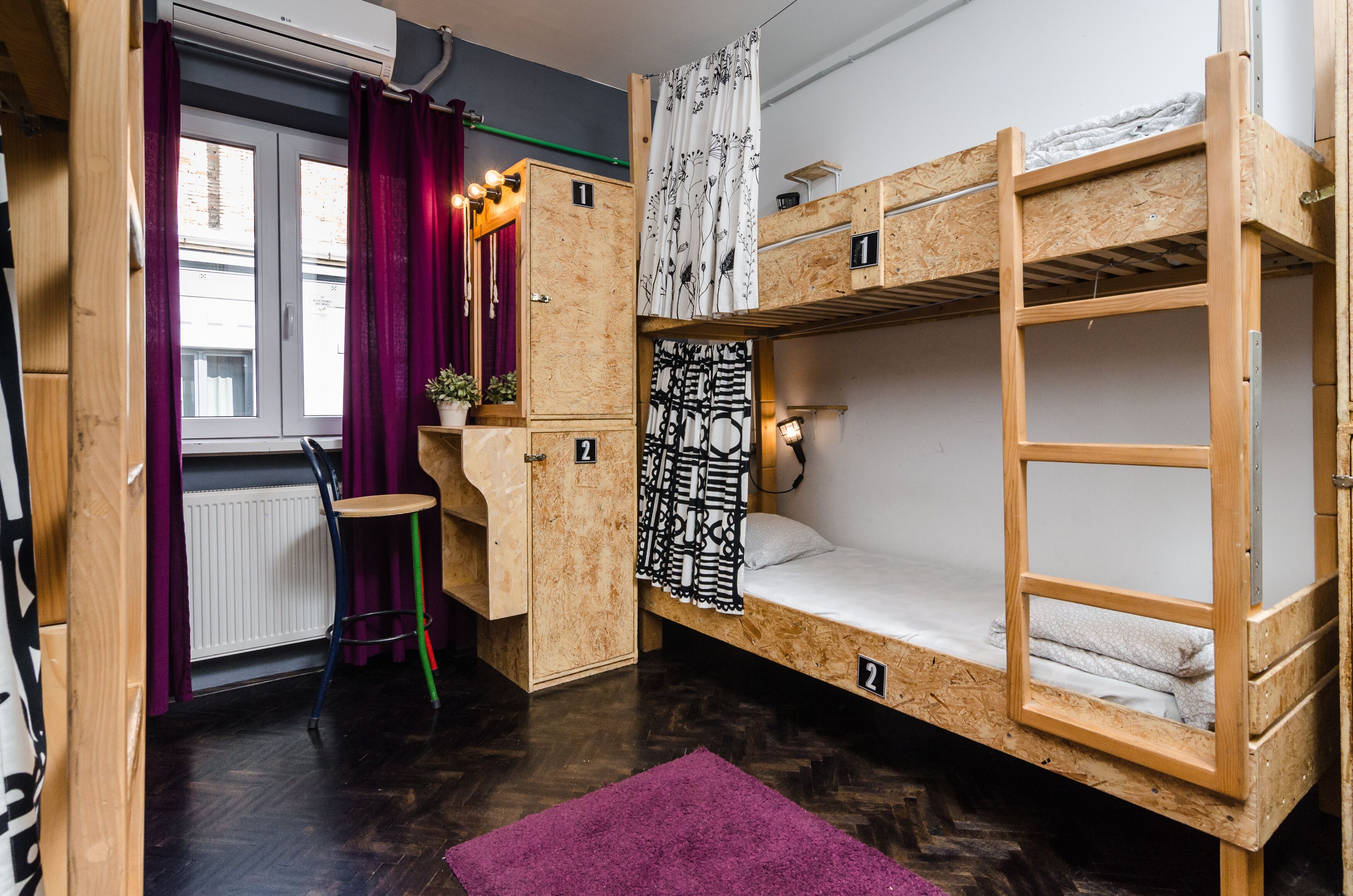 A compact room with bunk beds, a small desk, a chair, and a radiator.