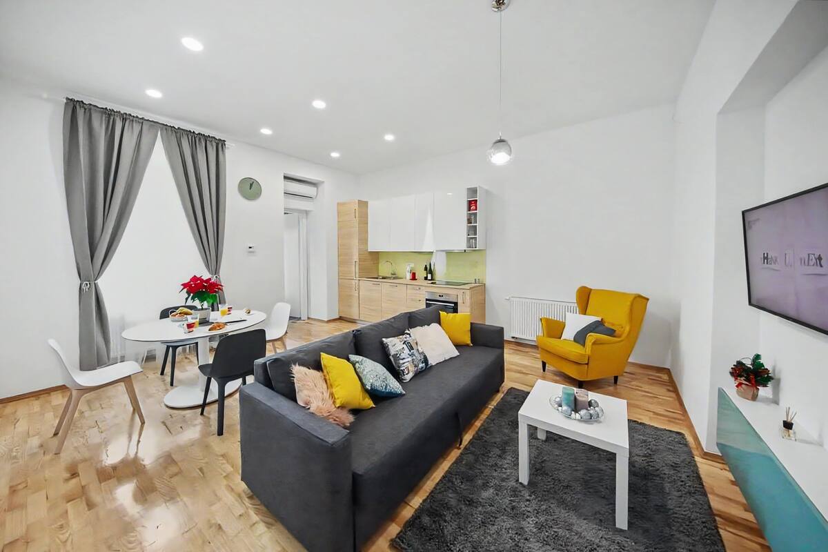 Ein modernes Wohnzimmer mit einer Couch, einem Esstisch und einer Küche im Hintergrund.