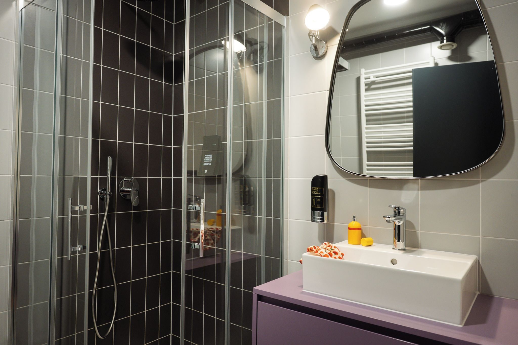 Un baño moderno con cabina de ducha de vidrio, un lavabo blanco con espejo y un lavamanos.