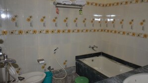 A bathroom with a toilet, bidet, bathtub, and sink. - Rainbow Guest House (Gaya)