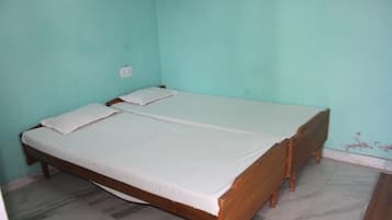 A single-bed room with a wooden frame, white bedding, and a light teal wall.
