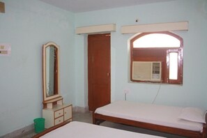 A bedroom with a single bed, a dresser, a mirror, and a door. - Rainbow Guest House (Gaya)