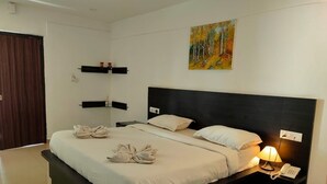 Ein modernes Hotelzimmer mit einem großen Bett, Nachttischen, einem Beistelltisch mit Lampe und einem Bild an der Wand.
