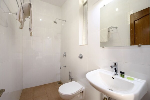 A modern bathroom with a shower, toilet, sink, and a mirror.