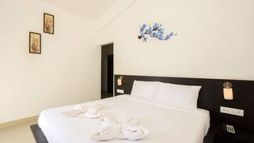 Habitación de hotel con una cama grande, ropa de cama blanca, cabecero negro y un teléfono montado en la pared.