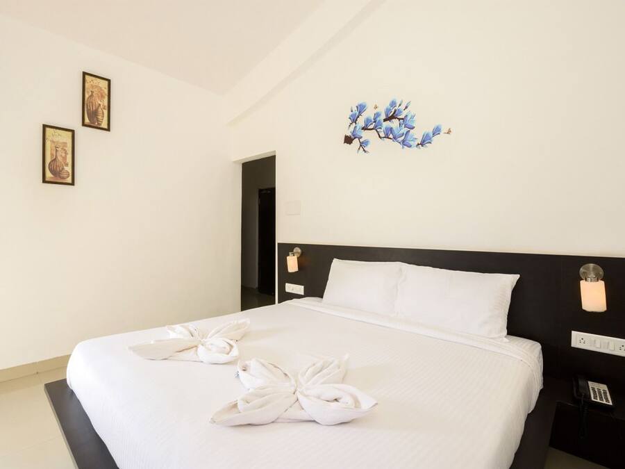 Habitación de hotel con una cama grande, ropa de cama blanca, cabecero negro y un teléfono montado en la pared.