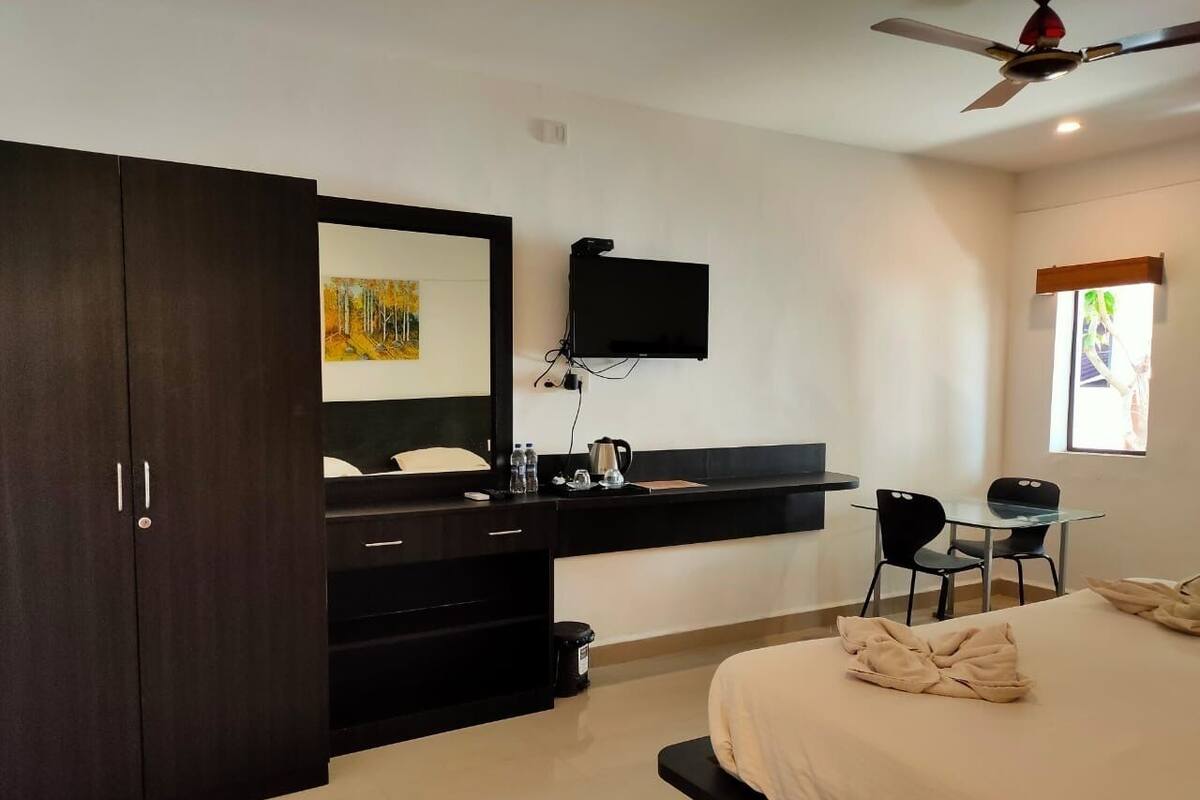 Een moderne slaapkamer met een bed, een bureau met een flatscreen televisie, een kledingkast en een raam met uitzicht.