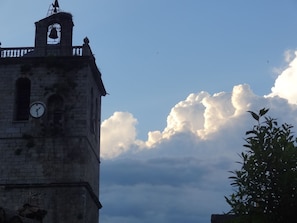A historic stone tower with a clock, a bell, and a balcony.