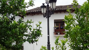 A street scene with a white building, a black street lamp, and green foliage. - Hostal La Solana (Arenas de San Pedro)