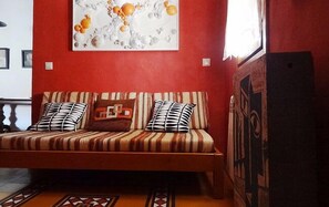Une pièce avec un mur rouge, un canapé orné de coussins à rayures et un élément décoratif fixé au mur au-dessus.