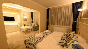 A hotel room with a bed, a desk, a chair, a TV, and a bathroom.