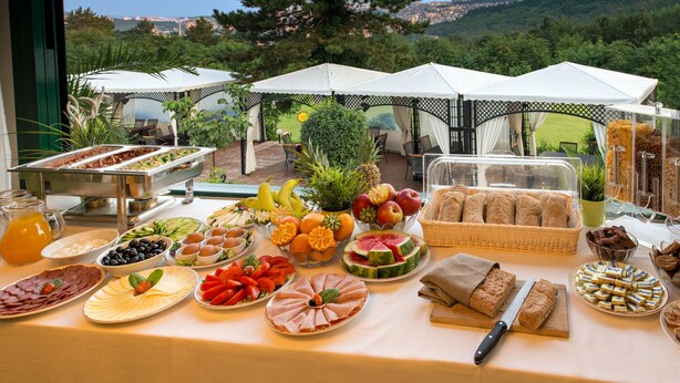 A buffet table with various food items and a scenic view in the background. - Park Hotel RAYA Garden (Veliko Tarnovo)