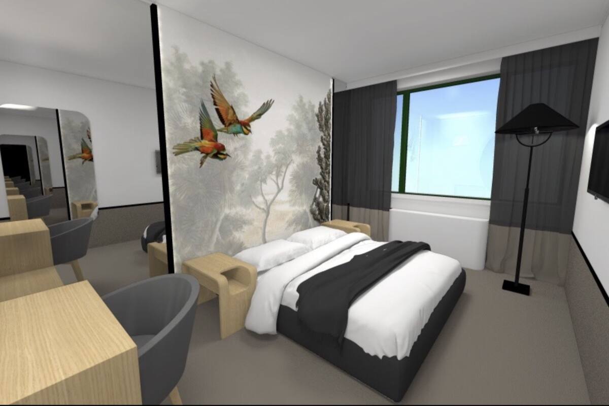 A modern hotel room with a large bed, a desk, a chair, and a large window with curtains.