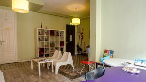 Una sala de estar con una estantería, una mesa y un comedor morado.
