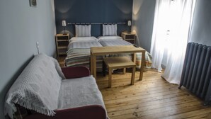 Un dormitorio con cama doble, una mesa de madera, un sofá rojo y un radiador.