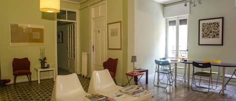 A spacious living area with a dining table, multiple chairs, and a white sofa.