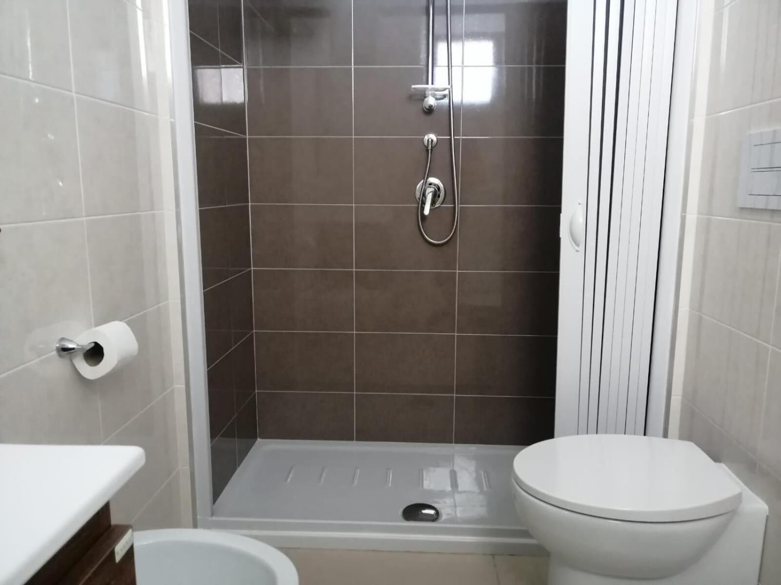 A bathroom with a shower, toilet, and a sink.