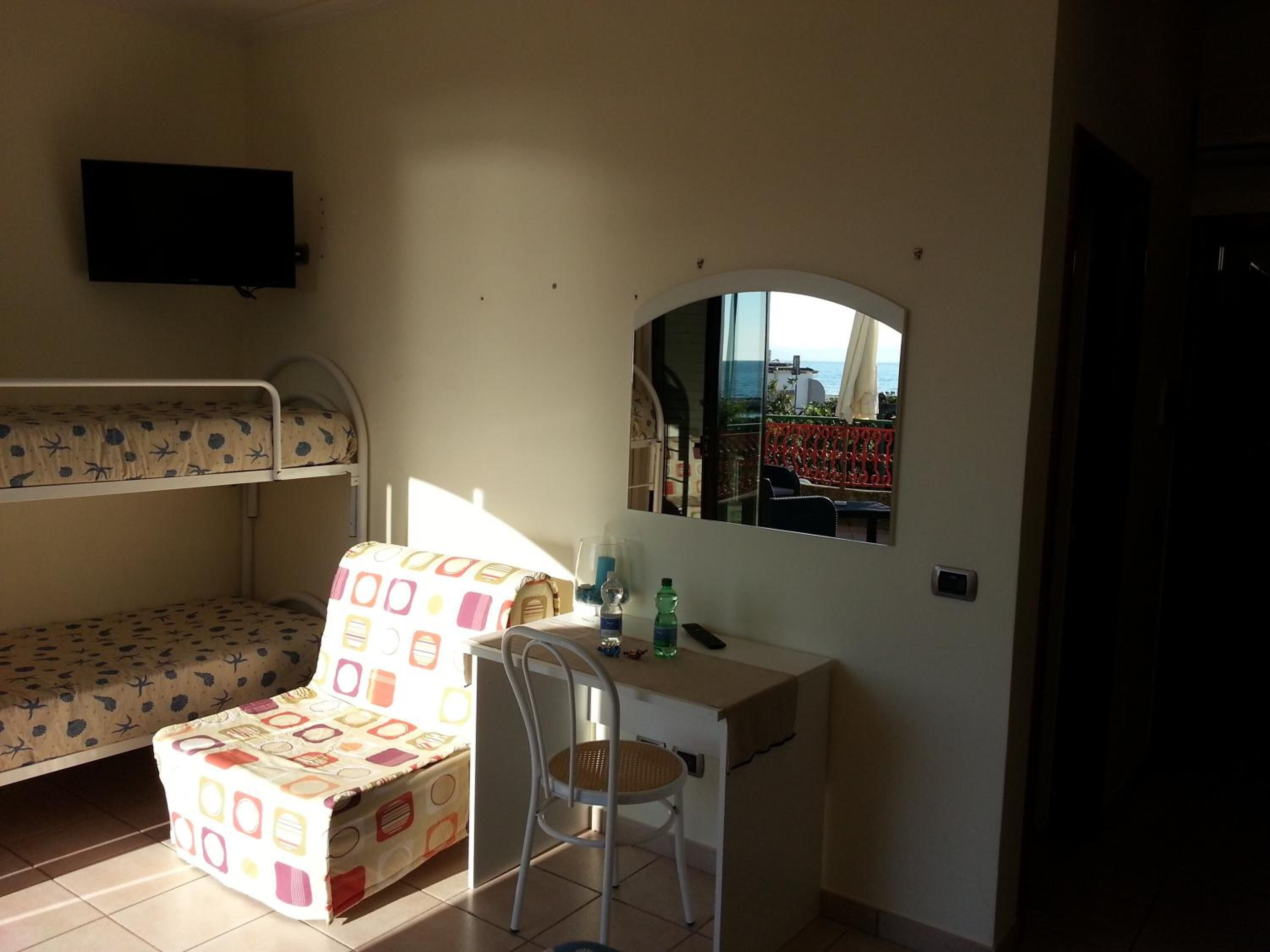 Una habitación pequeña con literas, un escritorio, una silla y un espejo.
