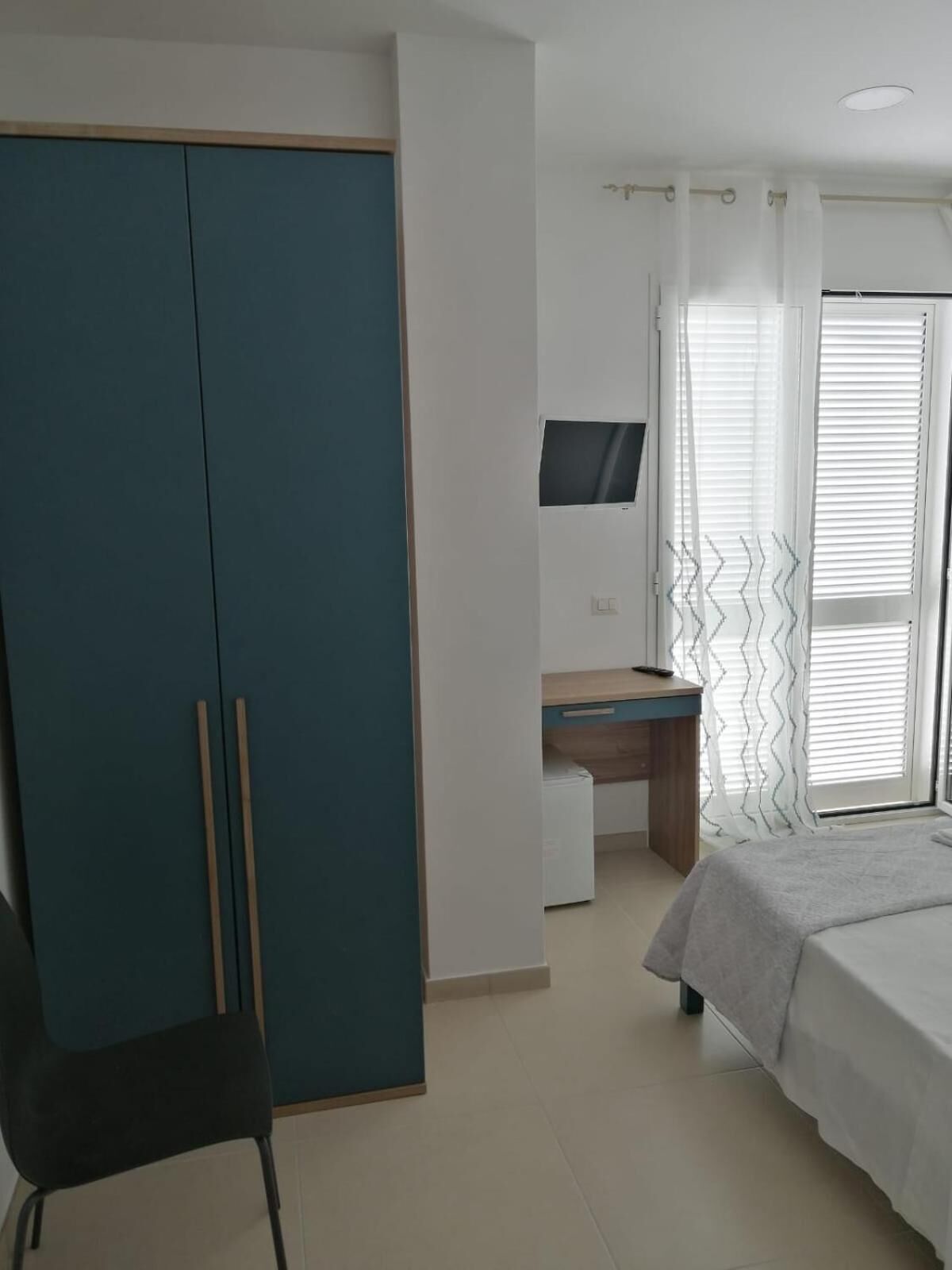 Un dormitorio con cama, escritorio, silla y armario.