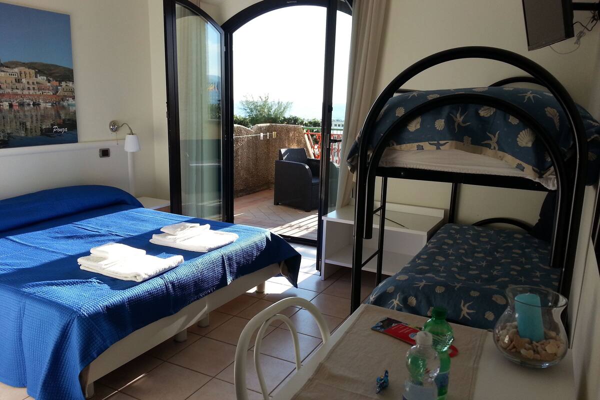 Ein Zimmer mit einem Bett, einem Tisch mit einer Flasche und einem Stuhl.
