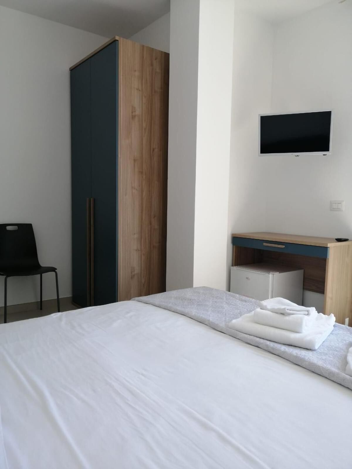 Een hotelkamer met een bed, een bureau, een kast en een televisie.
