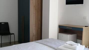 Een hotelkamer met een bed, een bureau, een kast en een televisie.