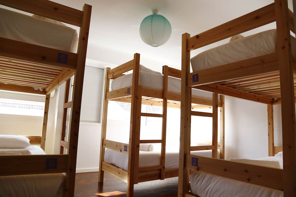 Une chambre avec des lits superposés, numérotés de 2 à 6, et une lanterne en papier suspendue au plafond.
