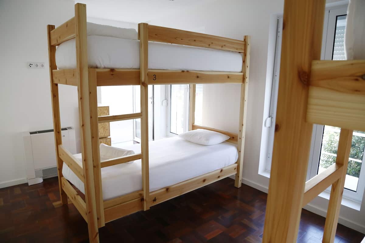 Un lit superposé avec une structure en bois et du linge de lit blanc.