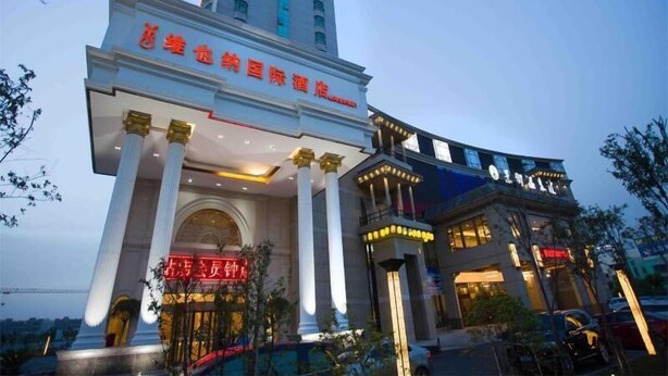 A hotel with a prominent entrance, large columns, and a modern building in the background. - Vienna International Hotel (Shanghai)