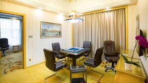 A conference room with a table, chairs, a chandelier, a painting, and a potted plant. - Vienna International Hotel (Shanghai)