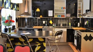 Una cocina moderna con salpicadero de azulejos negros, electrodomésticos de acero inoxidable y una isla central con taburetes.